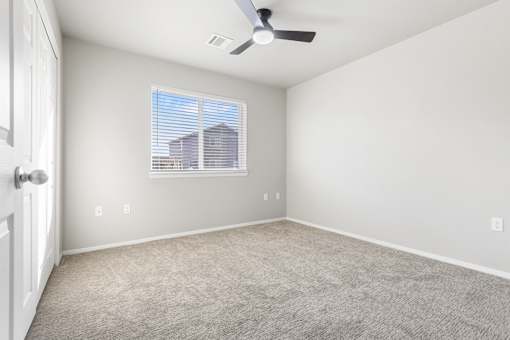 A room with a ceiling fan and a window with blinds.