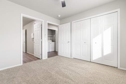 A room with white walls and a carpeted floor with a ceiling fan.