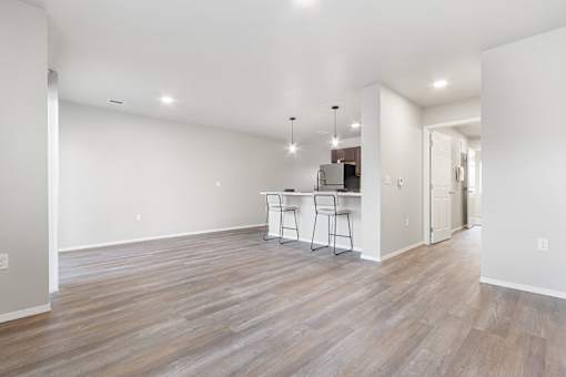 A room with wooden flooring and a kitchenette.