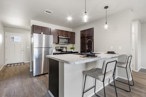 A kitchen with a white island and a stainless steel refrigerator.