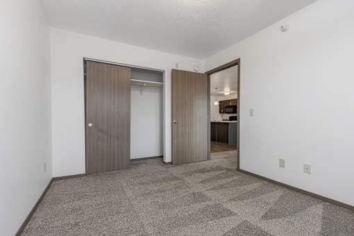 A room with a carpeted floor and two doors.