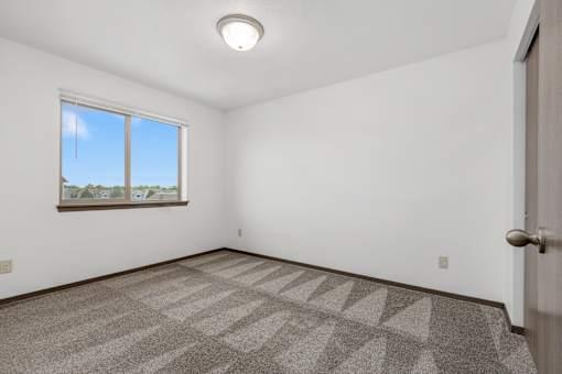 A room with a carpeted floor and a window.