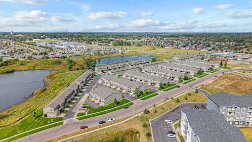 A large apartment complex sits next to a body of water with a road running through it.