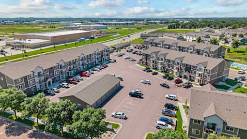 A large parking lot is surrounded by apartment buildings.