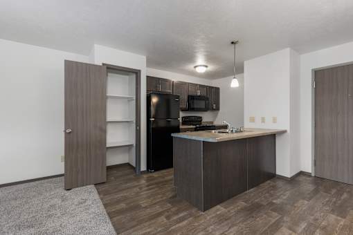 A kitchen with a brown door and a black fridge.