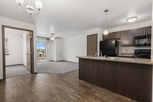 A kitchen with dark wood floors and white walls.