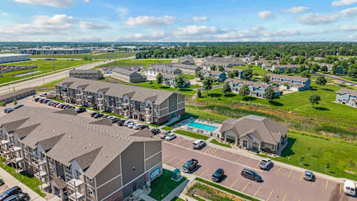 A large apartment complex with a swimming pool and a parking lot.