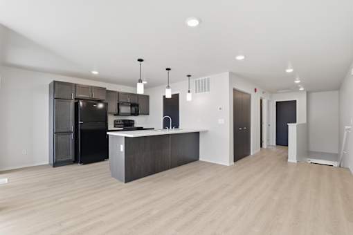 A kitchen with a black fridge and microwave, a white counter, and a black cabinet.