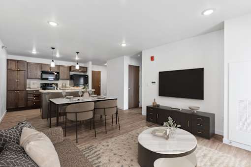 A modern living room with a kitchen area in the background.