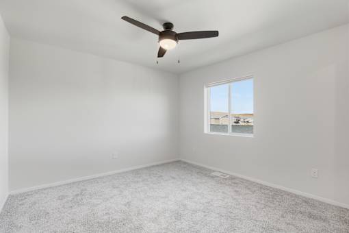 A room with a ceiling fan and a window with a view of the outside.