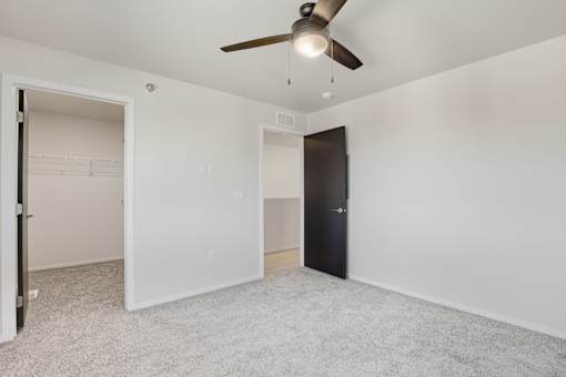 A room with a ceiling fan and a black door.