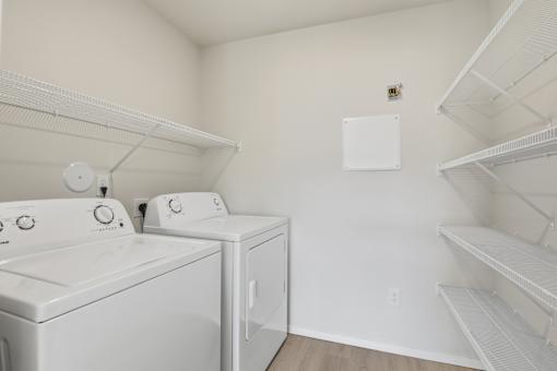 A laundry room with two washing machines and a shelf.