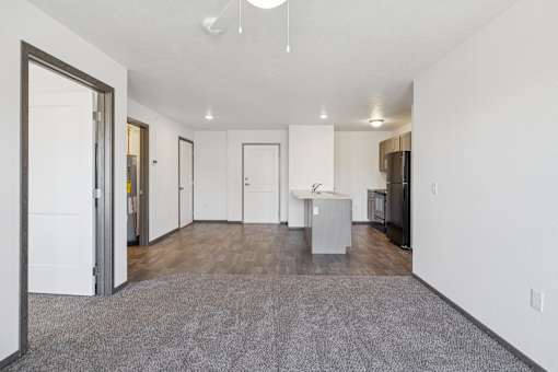 A spacious living room with a grey carpet and white walls.
