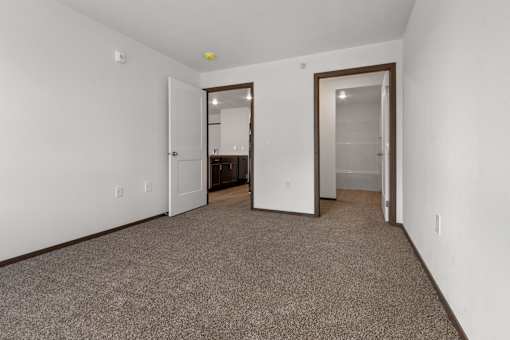 A room with a carpeted floor and two doors.