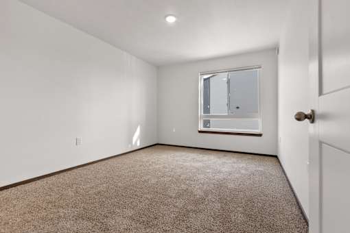 A room with a carpeted floor and a window.