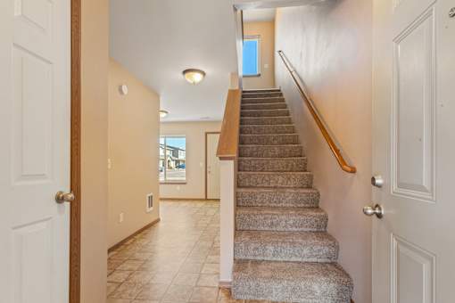 A staircase with a wooden handrail leads to a second floor.