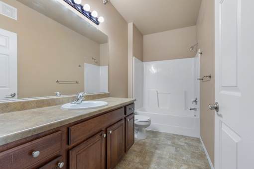 A bathroom with a sink, mirror, toilet, and bathtub.