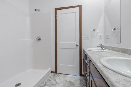 A white door is in a bathroom with a white tub and sink.
