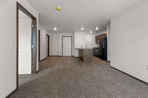 A spacious, empty room with a grey carpet and white walls.