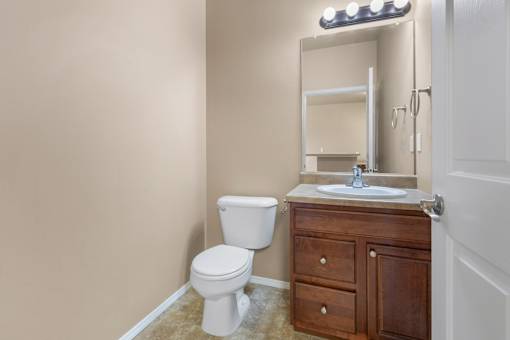 A bathroom with a toilet, sink, and mirror.