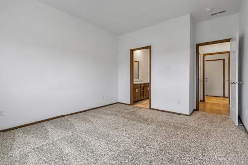 A carpeted room with a door and a cabinet.