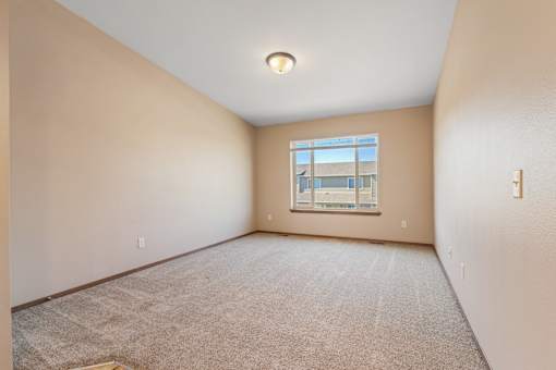A room with a carpeted floor and a window.