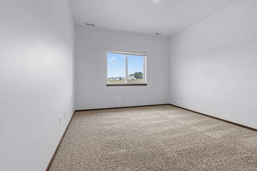 A room with a carpeted floor and a window showing a view of the outside.