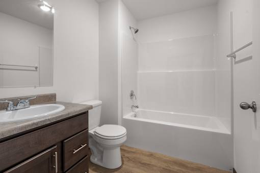 A white bathroom with a toilet, sink, and bathtub.