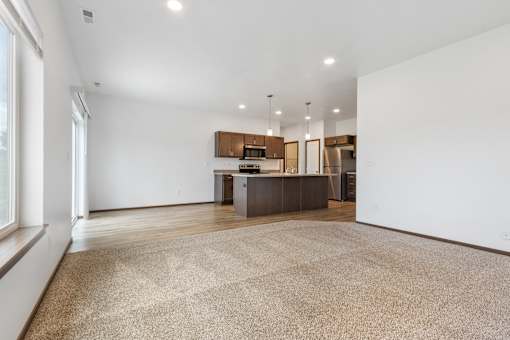 A spacious kitchen and living room with a large rug on the floor.