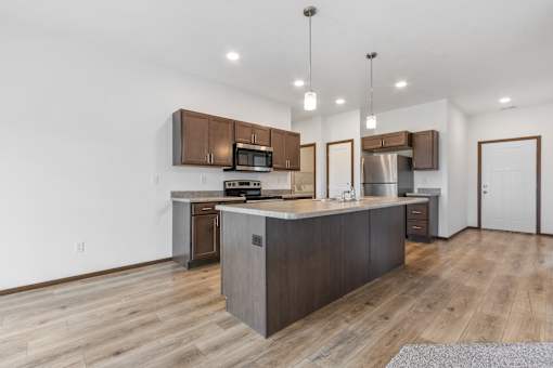 A modern kitchen with wooden floors and a central island.