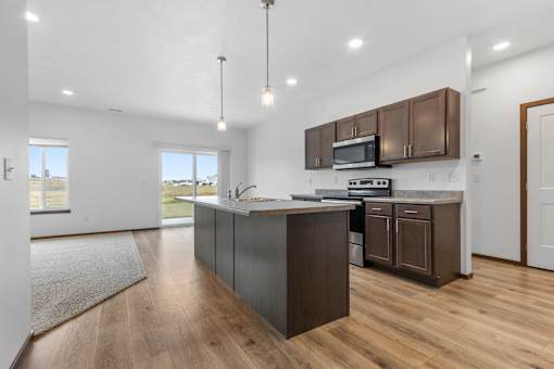 A kitchen with brown cabinets and a wooden floor.