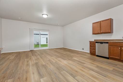 A room with wooden flooring and a window showing a view of a house.