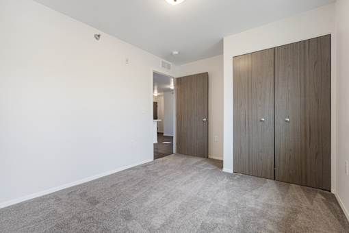 A room with a carpeted floor and two wooden doors.