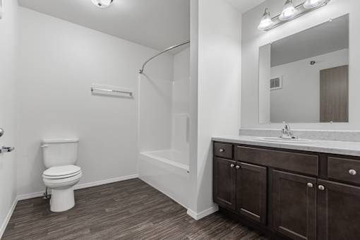 A white toilet is in a bathroom with brown cabinets.
