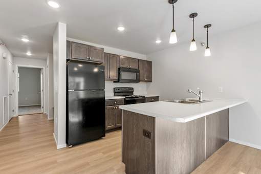A kitchen with a black fridge, microwave, and stove top oven.