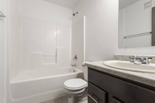 A white toilet sits next to a white bathtub in a bathroom.