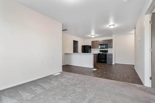 A spacious living room with a kitchenette in the background.