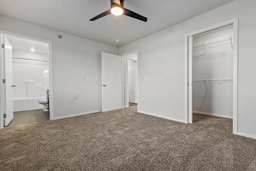 A room with a ceiling fan and carpeted floor.