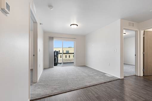 A spacious room with a carpeted floor and a window overlooking a balcony.