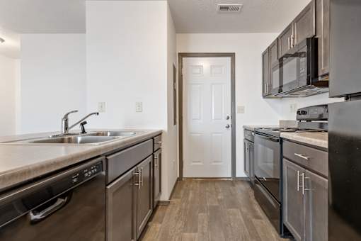 A kitchen with a white door and black appliances.