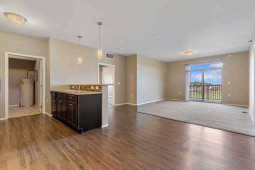 A spacious living room with a kitchen area in the background.