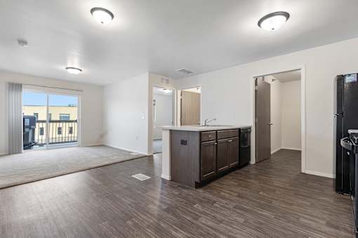 A spacious kitchen with dark wood floors and white walls.