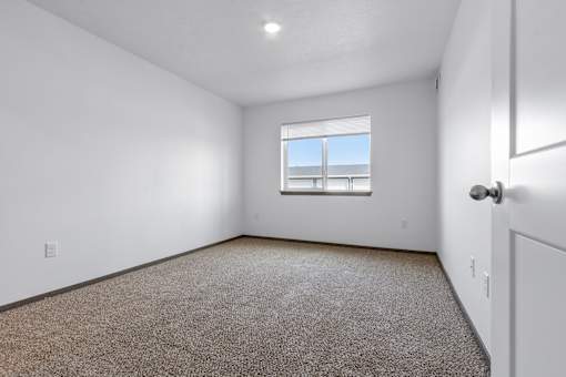 A room with a carpeted floor and a window.
