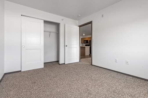 A room with a carpeted floor and two doors.