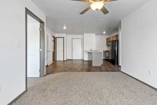 A spacious room with a ceiling fan and a carpeted floor.