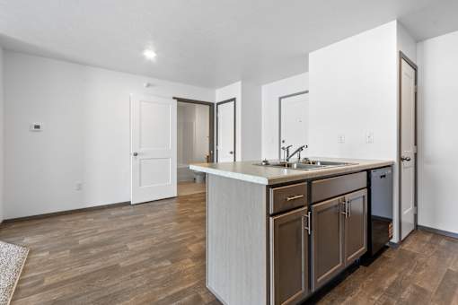 A kitchen with a white counter top and wooden floors.