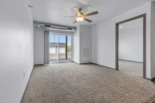 A room with a ceiling fan and carpeted floor.