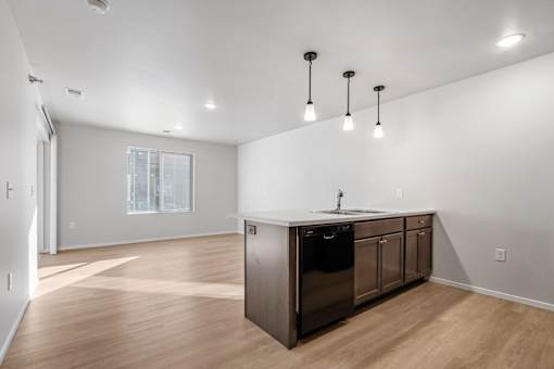 A kitchen with a wooden floor and a black dishwasher.