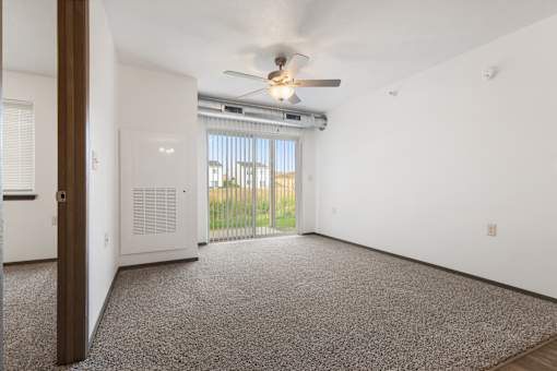 A room with a ceiling fan and a window with blinds.