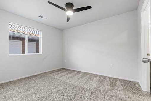 A room with a ceiling fan and carpeted floor.